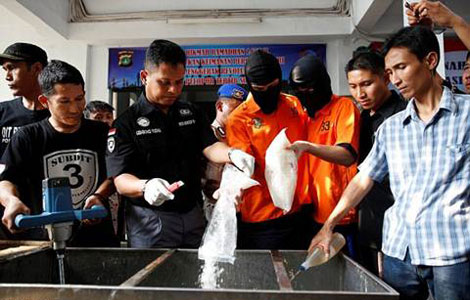 Nghi phạm buôn ma túy (áo vàng) phải tự tay tiêu hủy tang vật thu được sau chiến dịch trấn áp tội phạm ở Jakarta, Indonesia (Ảnh: SCMP)